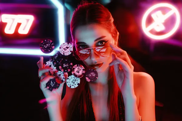 A glamorous woman holding casino chips in a neon-lit environment, representing the premium online casino atmosphere of RAJ123.
