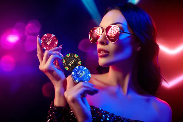 A woman smiling while playing online games on her laptop, surrounded by neon casino elements, showcasing RAJ123’s diverse game collection.